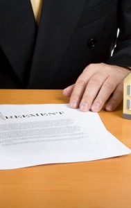 real estate agreement with an "as is" caveat emptor being slid across a table.