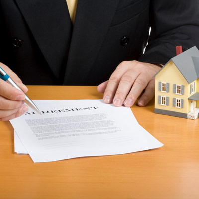 real estate agreement with an "as is" caveat emptor being slid across a table.
